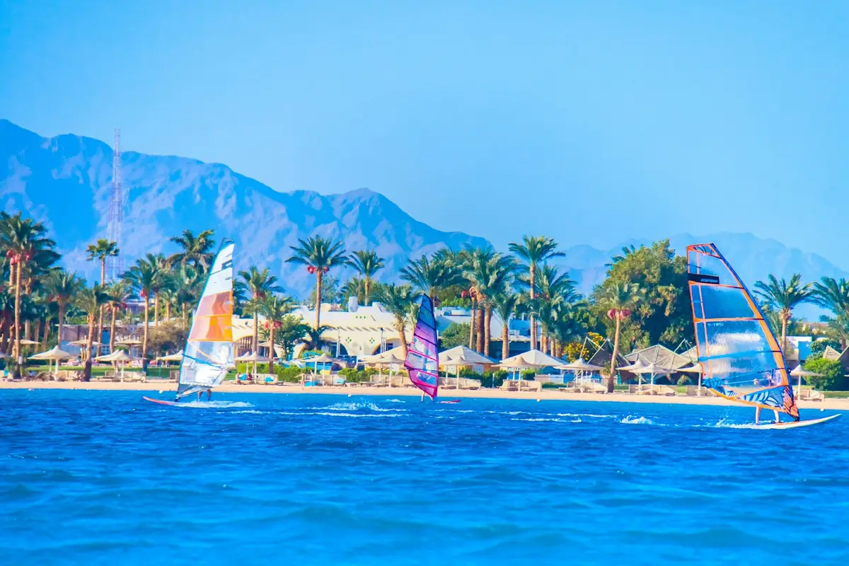 Windsurferzy na lagunie w Dahabie na tle palm i gór