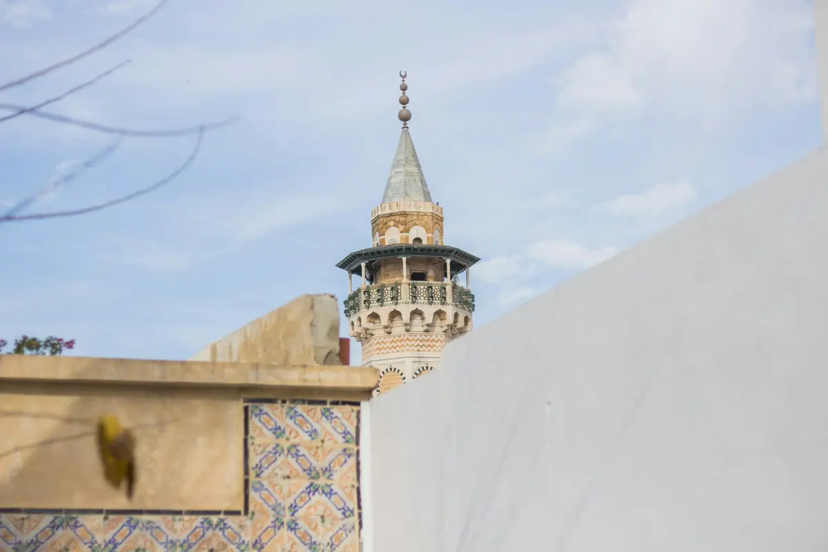 Minaret nad białymi murami medyny w Tunisie