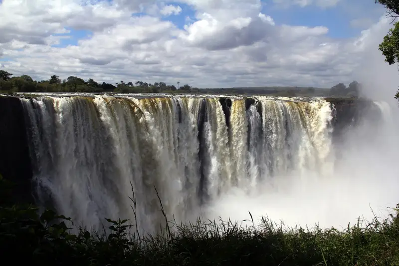 Szeroka kurtyna Wodospadów Wiktorii z chmurą wodnego pyłu, widok od strony Zimbabwe