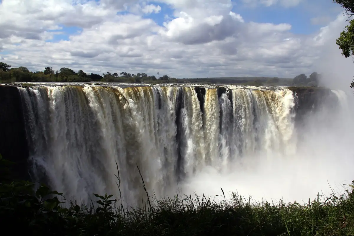 Szeroka kurtyna Wodospadów Wiktorii z chmurą wodnego pyłu, widok od strony Zimbabwe