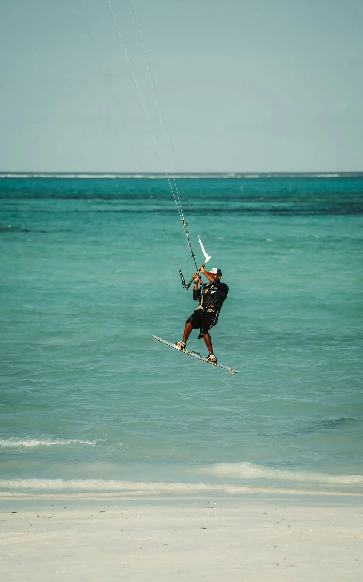 Kitesurfer nad turkusową wodą na plaży Paje na Zanzibarze