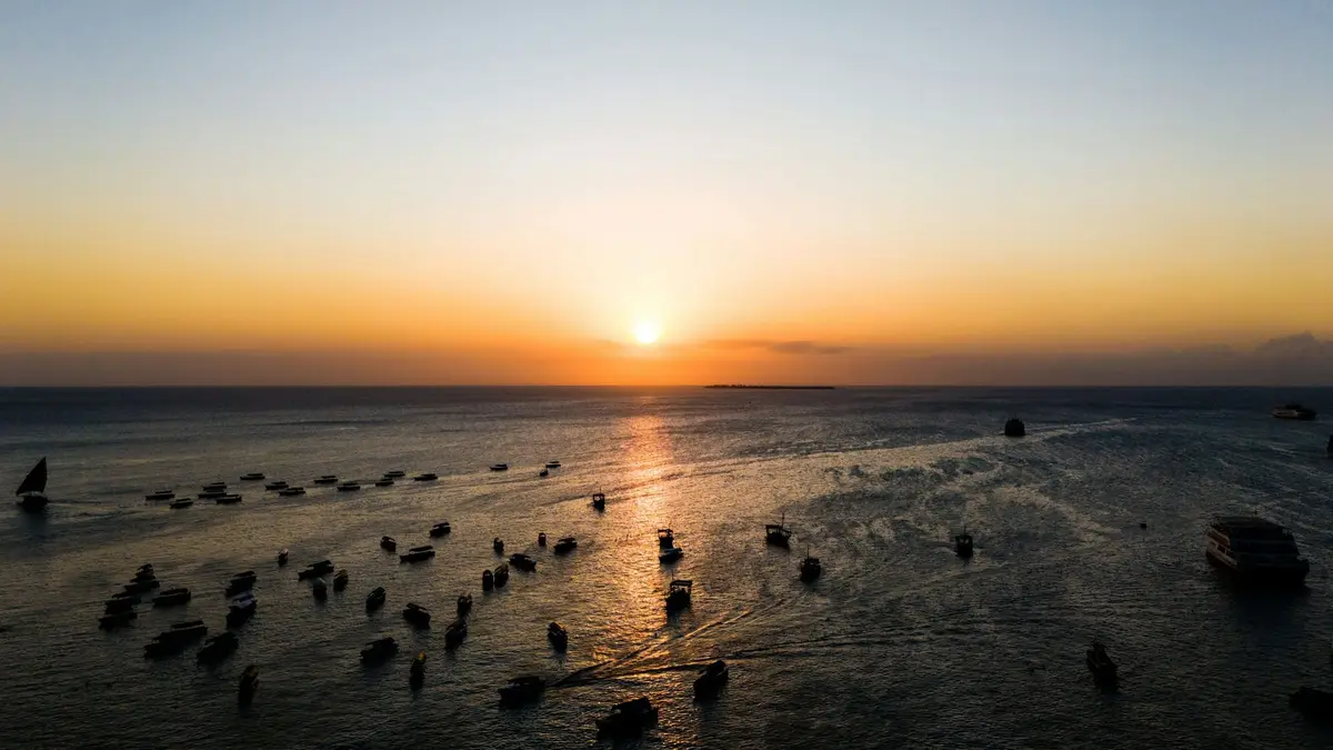 Zachód słońca nad oceanem i łodziami przy Stone Town